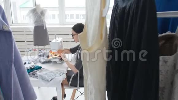 爱好缝纫和一个小企业的概念年轻漂亮的女裁缝缝在缝纫机上裁缝做衣服视频的预览图