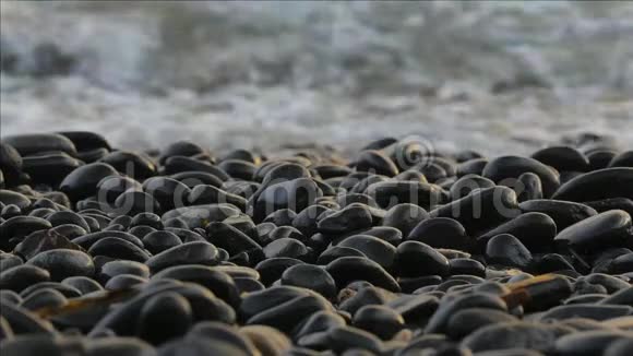 有泡沫的海浪在卵石海岸上翻滚特写镜头视频的预览图