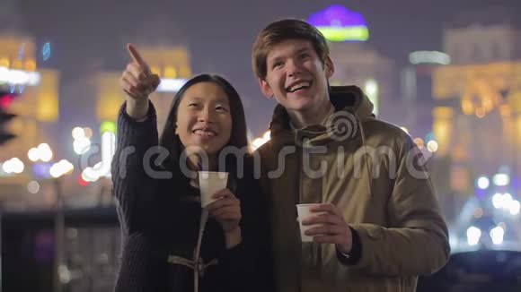 年轻的幸福夫妇享受夜街表演喝茶在户外玩得开心视频的预览图