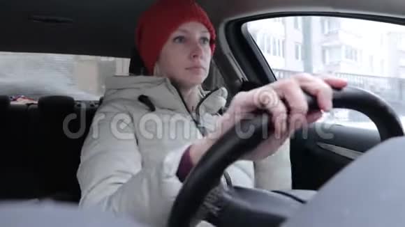 穿着冬装戴着橙色针织帽子的女人在冬道上开车视频的预览图