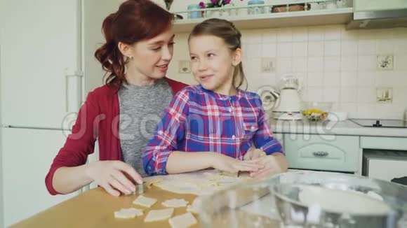 快乐的母亲和可爱的小女儿一起聊天一起做饼干用面包房的形式做面团视频的预览图