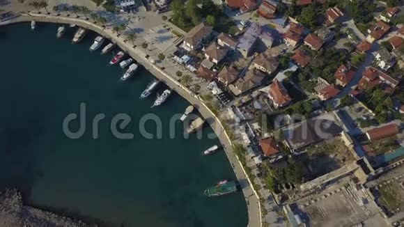 停泊船只的俯视图无人机飞向前船在波浪上摇摆在岸上低矮的房子视频的预览图