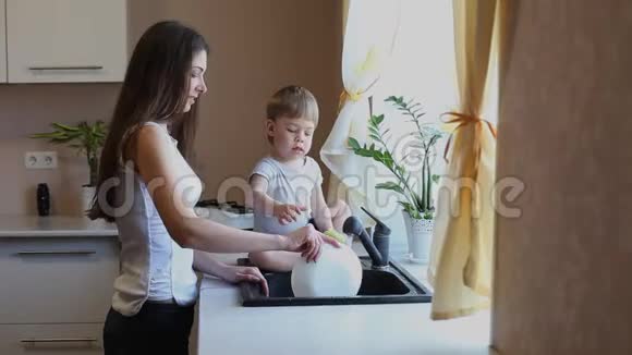 男孩和妈妈在厨房里洗蔬菜视频的预览图