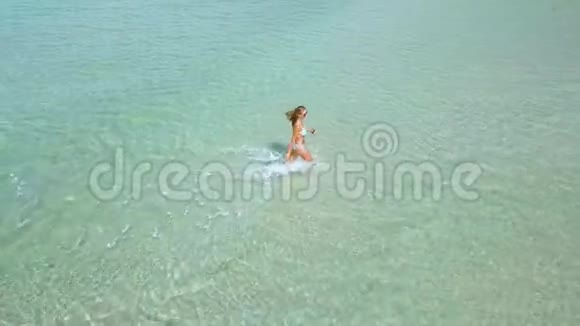 美丽的女士穿着比基尼在透明的海水中漫步夏季海滩绿松石海中的无人观女视频的预览图