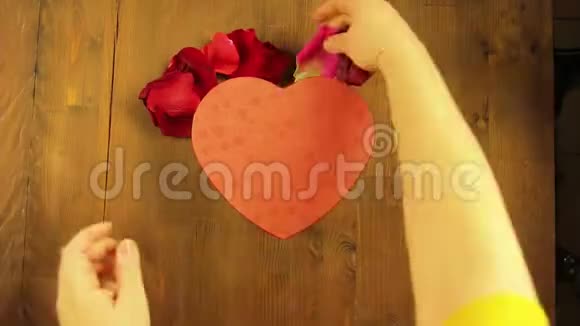 女孩用玫瑰花瓣把一颗心放在木桌上时间跨度视频的预览图