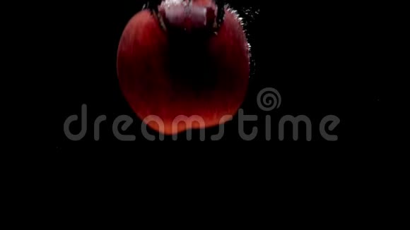 一个红苹果落在黑底的透明水中视频的预览图
