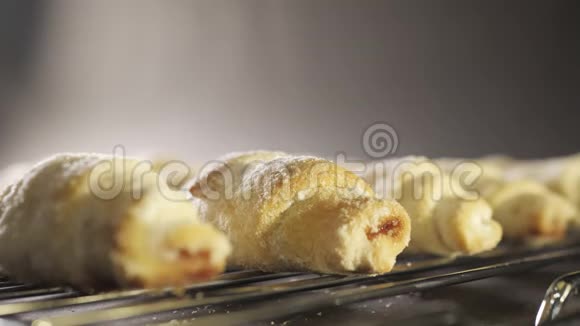 面包师在美味的饼干上涂上粉状的糖霜粉新鲜牛角面包上面有糖粉慢慢视频的预览图