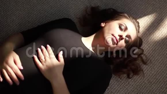 年轻的孕妇躺在窗户附近阳光照射在女人身上视频的预览图