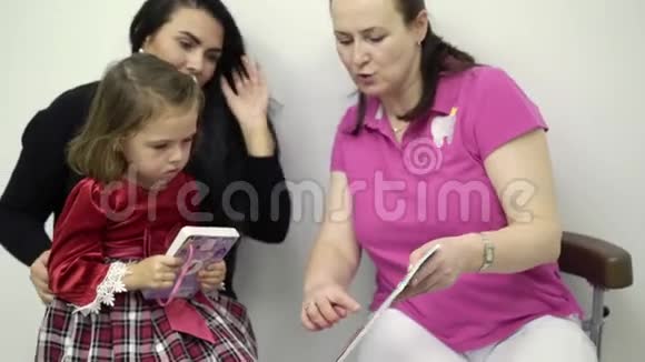 小女孩和牙医医生看贴有贴纸的书视频的预览图