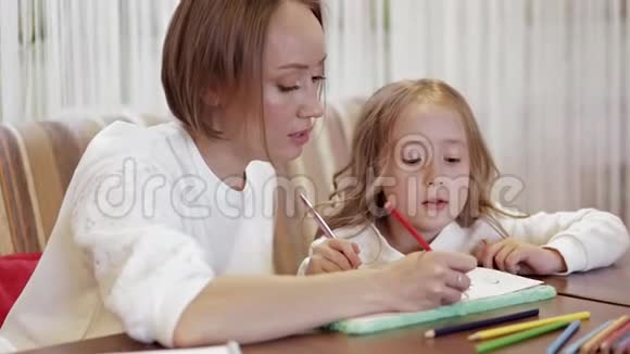 年轻积极可爱的母亲和她美丽的小女儿一起画画视频的预览图
