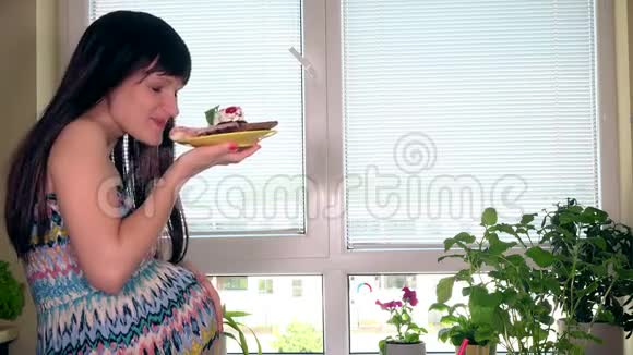 年轻的孕妇坐在家门口吃美味的蛋糕视频的预览图