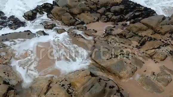 缓慢移动的空中无人机在葡萄牙海滩上的海浪拍打着岩石视频的预览图