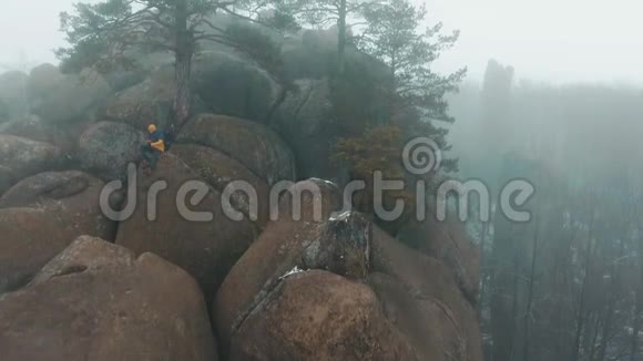 男人用一部智能手机坐在山顶上上面布满了雾视频的预览图