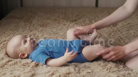 婴儿按摩妈妈给孩子做体操新生儿和母亲在床上视频的预览图