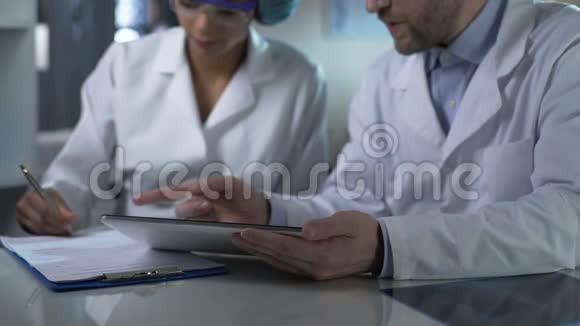 男医生拿着药片给女助手指示记下视频的预览图