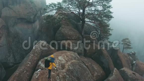 穿黄色夹克的人爬满了雾的岩石视频的预览图