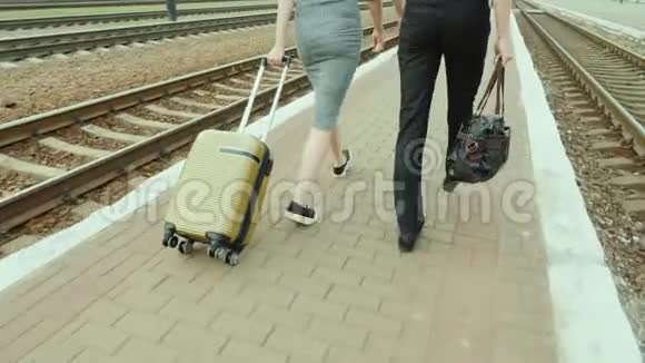 两个商人沿着铁路走带着行李在框架中只有腿是可见的Stadicam视频的预览图