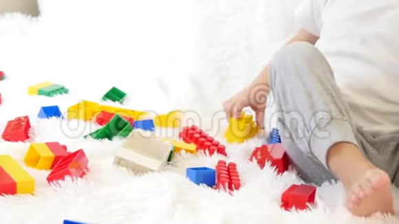 孩子玩彩色积木坐在沙发上的白色背景孩子和玩具特写运动相机滑块视频的预览图