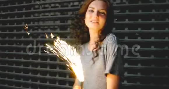 女孩在金属栅栏前的街道上和火花匠玩视频的预览图