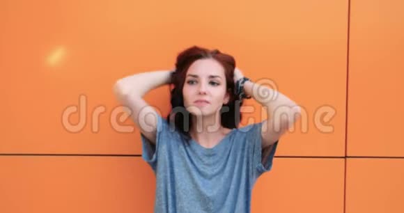 橙色墙前自然漂亮的红发女孩肖像课后学生视频的预览图