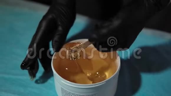 师父从一个白色的罐子里拿出一个厚厚的黄色焦糖浆视频的预览图