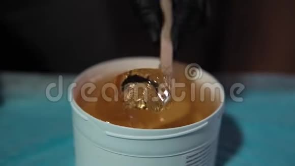 师父从一个白色的罐子里拿出一个厚厚的黄色焦糖浆视频的预览图