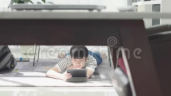 亚洲男孩在平板电脑上玩孩子在家用笑脸做平板电脑视频的预览图