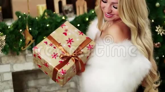 一个金发女人看着一份漂亮的圣诞礼物视频的预览图