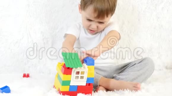 孩子建造一个彩色积木玩具屋坐在白色背景上特写孩子和玩具视频的预览图
