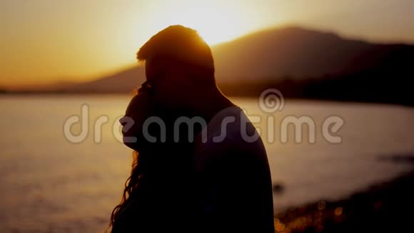 一对夫妇在海滩上一起享受浪漫的日落黄昏海滩上的几个剪影日落的光微笑视频的预览图
