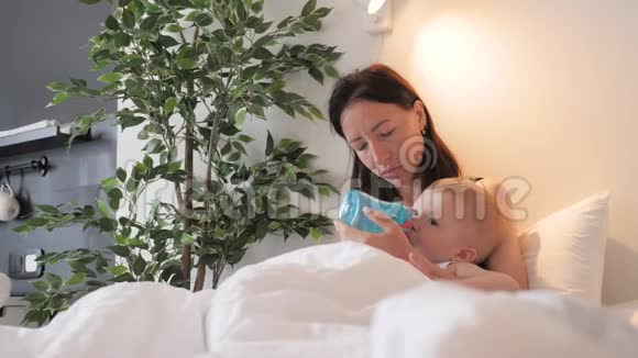 年轻的母亲在家里用一瓶牛奶喂她的小儿子视频的预览图