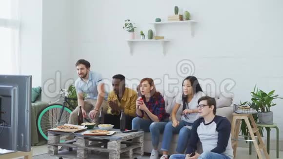 一群快乐的朋友在家里看体育比赛当他们最喜欢的球队获胜时他们跳着喊视频的预览图