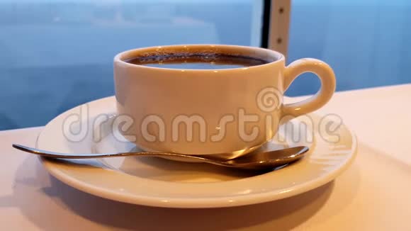 一杯咖啡用勺子放在一张桌子上当游轮行驶时背景是大海视频的预览图