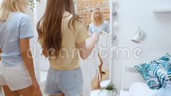 两个快乐的年轻女朋友在家里试穿衣服视频的预览图