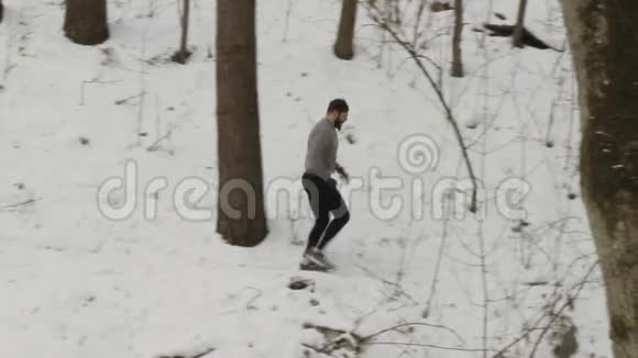 年轻强壮的运动员在森林里的山丘上的树木间奔跑视频的预览图