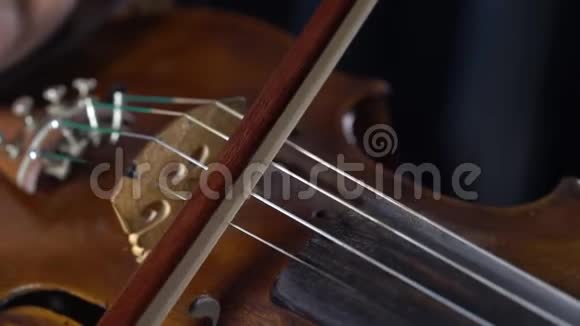 在一个棕色小提琴女孩手中弹奏琴弦快关门黑色背景视频的预览图
