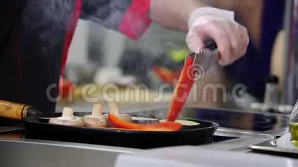 在厨房工作的厨师把锅里的蘑菇和蔬菜加热视频的预览图