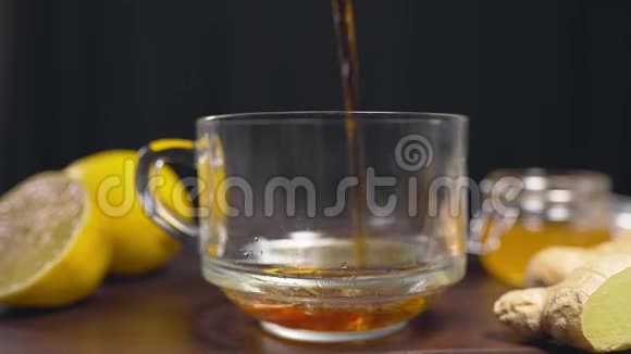 将热红茶倒入玻璃杯中加入柠檬生姜和蜂蜜的维生素茶以防生病饮用热视频的预览图