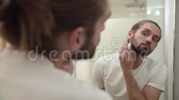 人在面部皮肤上涂抹剃须泡沫照镜子视频的预览图