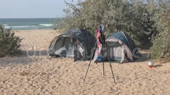 旅游营地帐篷和一辆汽车在旅游停车场论摄影师悬挂泳衣的三脚架移动视频的预览图