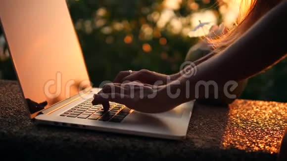 关闭女子打字在笔记本电脑键盘再次美丽的海滩日落4K慢动作泰国普吉岛视频的预览图