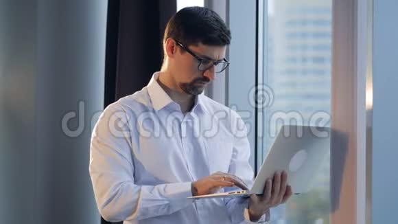 一个集中的商人在笔记本电脑上打字看着窗外视频的预览图