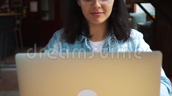 漂亮的黑发女人在咖啡馆里用笔记本电脑视频的预览图