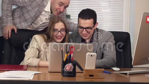 快乐有趣的年轻人男人和女人在办公室看着笔记本电脑笑视频的预览图