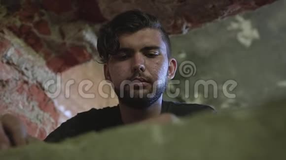 一个无家可归的人带着悲伤和悲伤的脸看着旧照片它位于一座废弃的建筑里视频的预览图