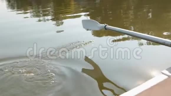 特写小船转弯用一只桨划阳光被水反射视频的预览图
