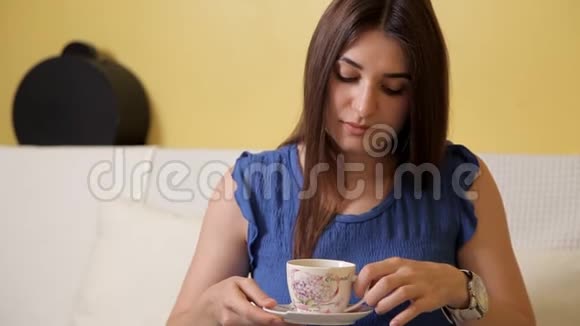 一个穿着蓝色西装的年轻女孩坐在沙发上喝着茶想着什么茶饮视频的预览图