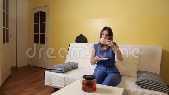 一个穿着蓝色西装的年轻女孩坐在沙发上喝着茶想着什么茶饮视频的预览图