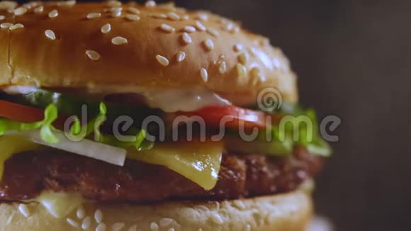 巨大美味的新鲜汉堡在黑烟背景上旋转奶酪汉堡宏观视野美国快餐不健康视频的预览图