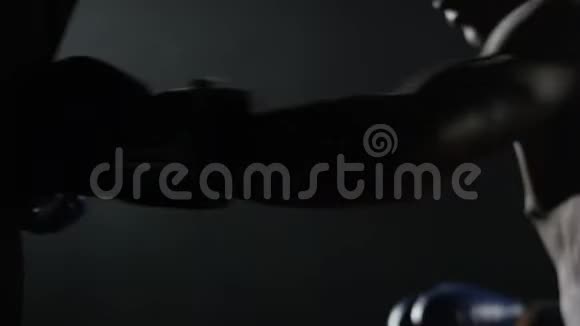 黑色背景上的拳击手和拳击袋拳击袋中的男拳击手年轻的肌肉拳击手视频的预览图